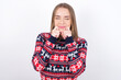 © Roquillo - Pleased Young caucasian girl wearing christmas sweaters on white background with closed eyes keeps hands near cheeks and smiles tenderly imagines something very pleasant