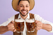 Young man in traditional German clothes with beer on lilac background