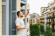 © Daniel Gonzalez/Stocksy - Man greeting friend from balcony