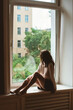© Lyuba Burakova/Stocksy - Woman sitting on a windowsill