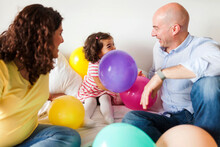 Family  On Bed Playing With Balloons
