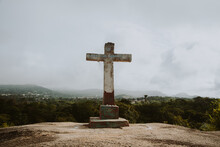 Christian Cross On Top Of The Hill With A Little Town At The Background, Crucifixion, Religious Concept 