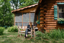 Woman Writing By A Log Cabin