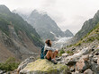 © ZHPH Production/Stocksy - Female traveller sitting on the rock  in mountain area