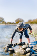 Child Playing Outdoors In A River In Autumn