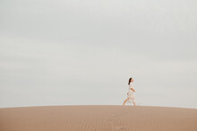 Woman In Dress Walking In Desert.