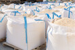 Bags with bulk construction materials standing in rows in outdoor storage.