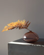 © Ellie Baygulov/Stocksy - Rounded glass vase with dried fern leaf