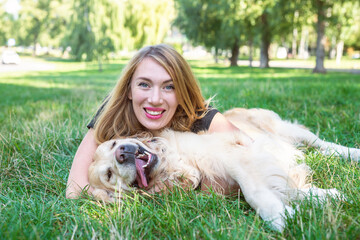 Wall Mural -  blonde and dog retriever lie on green grass