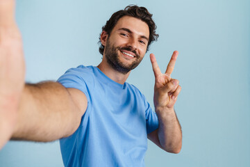 Young brunette man with bristle gesturing while taking selfie photo