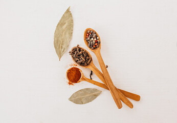 Spices in a wooden spoon. Herbs, curry, saffron, turmeric, cinnamon, bay leaf, peppers for cooking on a white background