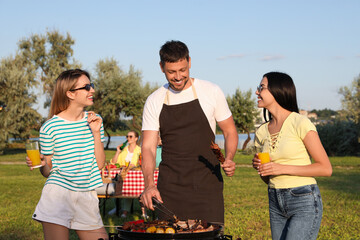 Canvas Print - Group of friends cooking food on barbecue grill in park