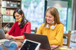 © MandriaPix - Two young women studying in library together, preparing for exams. multiethinc university students. two female college students studying with facemasks
