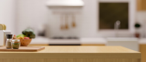 Light wooden kitchen countertop with set of seasoning and space for montage over blurred kitchen background.