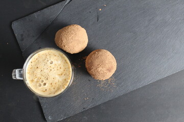 Canvas Print - coffee with dessert cup with coffee with foam and next to them are chocolate cakes with cocoa on a black stone background with a place for text. breakfast