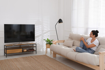 Canvas Print - Woman watching television at home. Living room interior with TV on stand