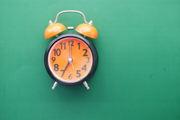 Wall Mural - orange old alarm clock on green background 