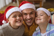 © wavebreak3 - Portrait of caucasian father and two sons wearing santa hat smiling at home during christmas