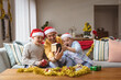 © wavebreak3 - Caucasian father and two sons opening gift box during video call on digital tablet during christmas