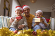 © wavebreak3 - Portrait of caucasian father and two sons holding christmas gifts smiling at home during christmas