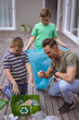 © wavebreak3 - Caucasian father and two sons collecting plastic materials in a bag outdoors