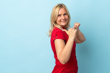 Wall Mural - Middle age woman isolated on blue background pointing to the side to present a product