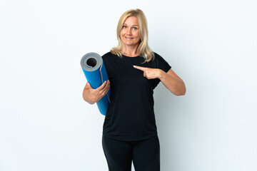 Wall Mural - Middle age woman going to yoga classes while holding a mat isolated on white background with surprise facial expression