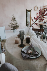 Elegant aesthetic Christmas dinner serving concept. Bright living room interior with table, beige linen table cloth, berries bouquet. Christmas celebration evening