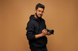 Happy indian photographer in black hoody with proffesional camera on background