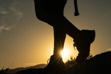 Silhouette Of The Legs Of A Woman Doing Trekking In The Mountain With The Sun Creating A Sunstar With Her Foot At Sunset