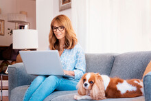 Middle Aged Woman Sitting On The Stofa At Home And Using Her Laptop