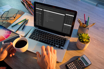 hands of caucasian male programmer sitting at desk and using laptop with coding on screen