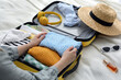 © New Africa - Woman packing suitcase for trip on bed, closeup