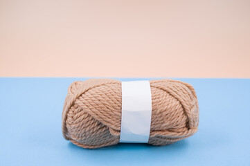 Canvas Print - Vertical shot of isolated soft beige yarn ball on an pastel blue background