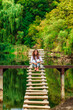 © KseniaJoyg - A young woman on a wooden ladder bridge on a forest mountain lake. Amazing summer landscape with a lake and a panoramic view of a mountain lake