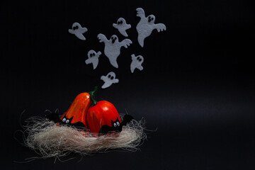 Halloween, holidays and decoration concept - Two orange pumpkins of different sizes standing on a fake straw leaning over each other with flying ghosts and bats on a black background with copy space