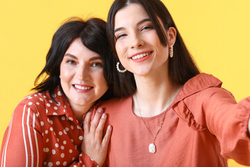 Sticker - Young woman with her mother taking selfie on yellow background, closeup