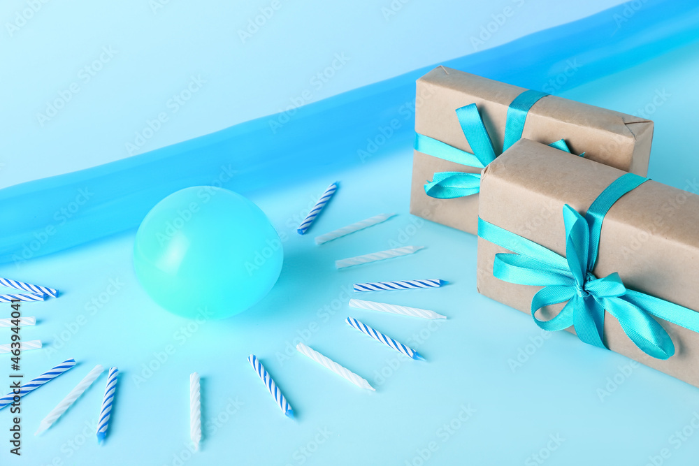 Gift boxes with balloons and party candles on color background