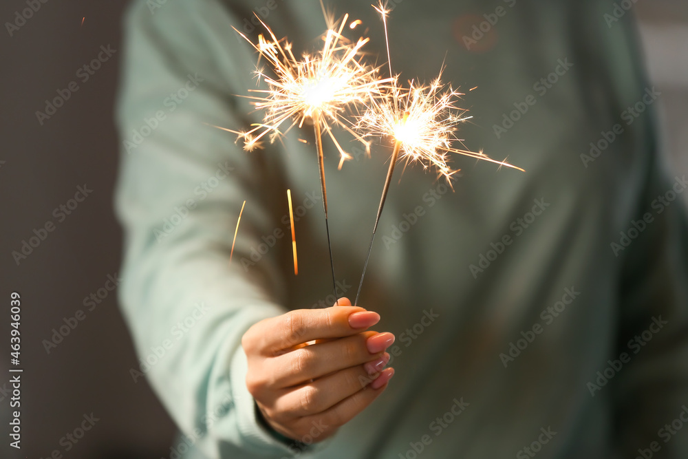 Woman with sparklers in room, closeup
