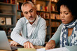 © Drazen - Mature man and his black female friend cooperating during research at university library.