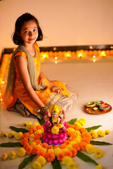 Poster - Cute indian little girl making decoration with flower and oil lamp for diwali festival at home.