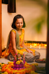 Poster - Cute indian little girl making decoration with flower and oil lamp for diwali festival at home.