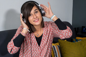 Wall Mural - pretty young woman listening to music  and relaxing while sitting on sofa