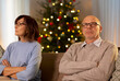 © Syda Productions - relationships difficulties, problem and people concept - unhappy senior couple sitting on sofa at home over christmas tree lights on background