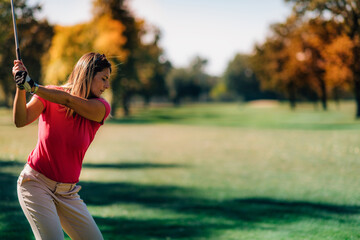 Wall Mural - Golfing lady in a golf swing, shot from behind