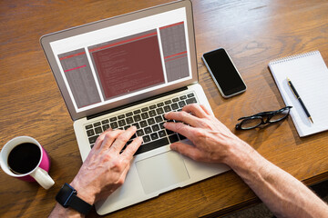hands of caucasian male programmer sitting at desk, using laptop with coding on screen