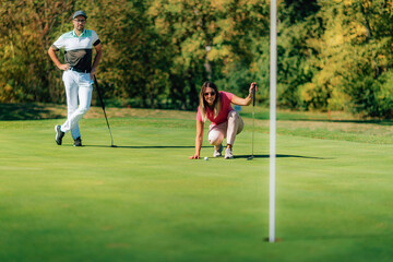 Wall Mural - Woman playing golf, reading the green