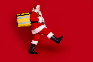 Wall Mural - Photo of positive excited retired man wear santa claus costume holding delivery backpack empty space isolated red color background