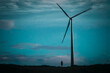 © Ekaterina - A wind turbine against a dark sky, a small silhouette of a man next to it