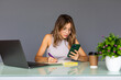 © F8  \ Suport Ukraine - Smiling young female employee work on laptop in modern office use cellphone gadget browsing wireless internet. Happy woman distracted from computer job text message on smartphone device.